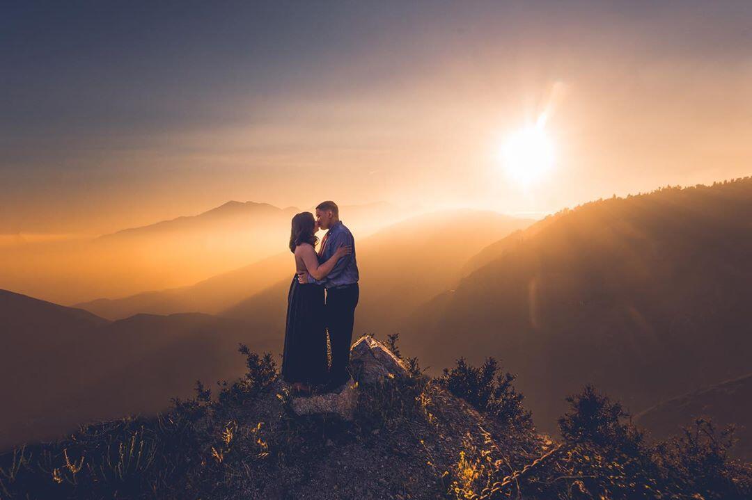 couple kissing on mountain at sunset