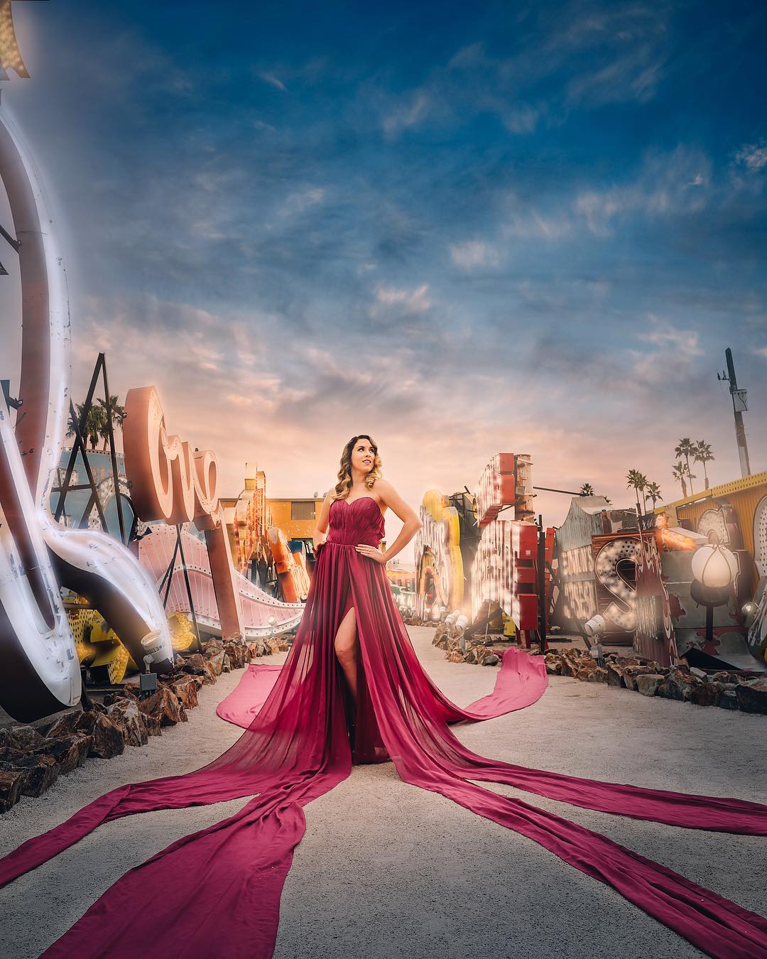 A woman dressed in wine colored gown in a well lit road