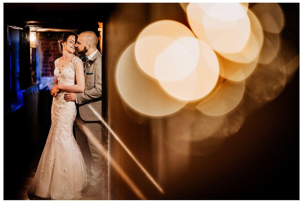 couple snuggling in a hallway with bokeh and lights