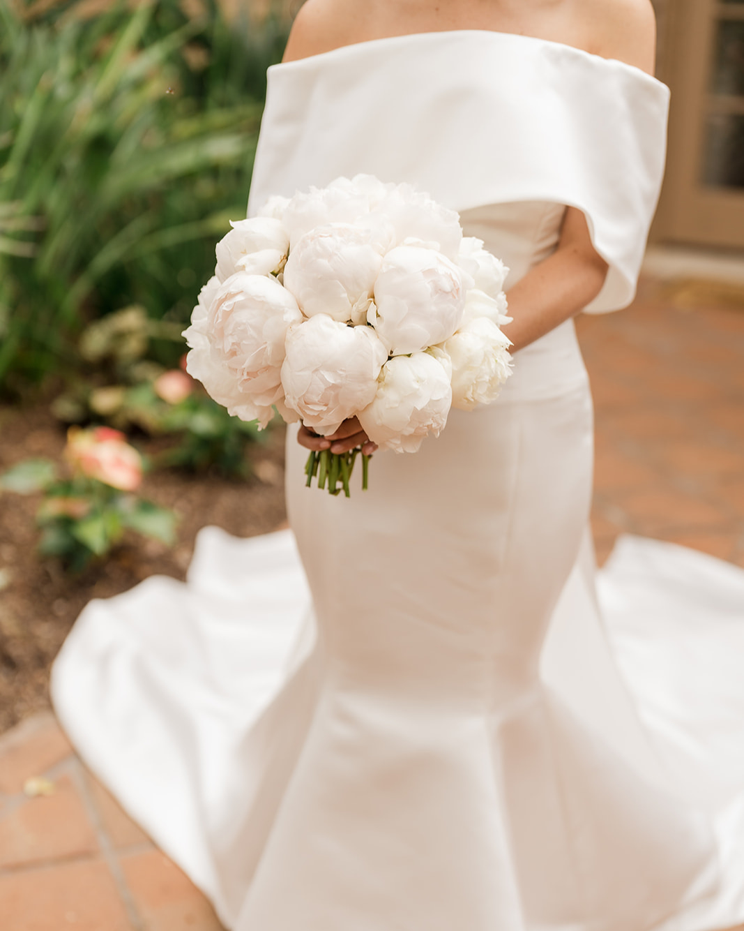 a cropped portrait of a bride in her wedding dress holding the bridal bouquet