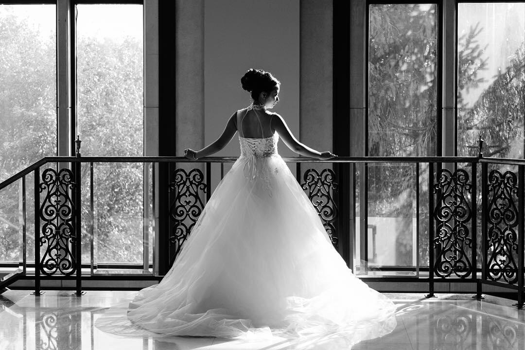 black and white photo of bride looking out over tall windows