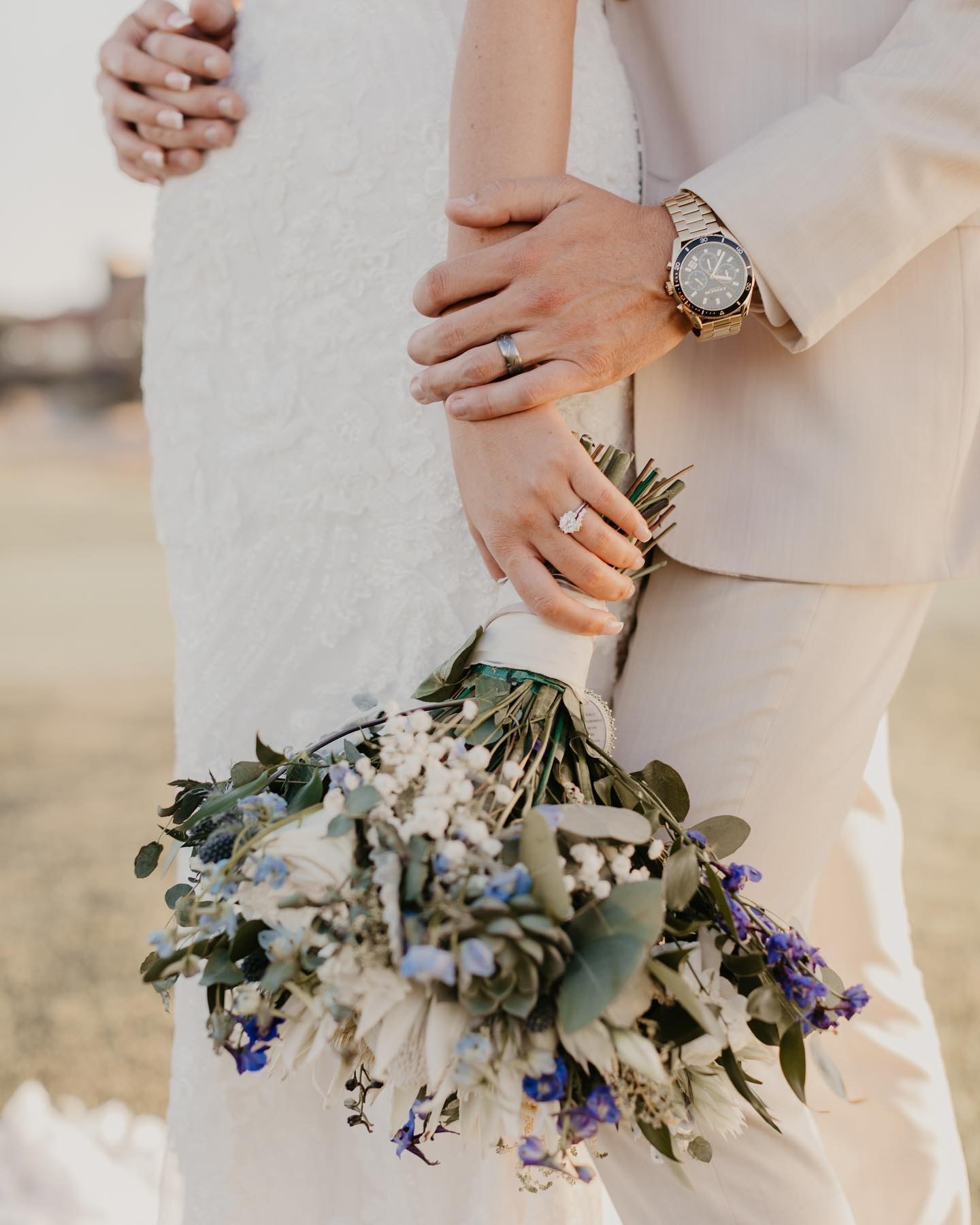 a bride holding her bouquet while the grooms hand is resting on the bride's wrist