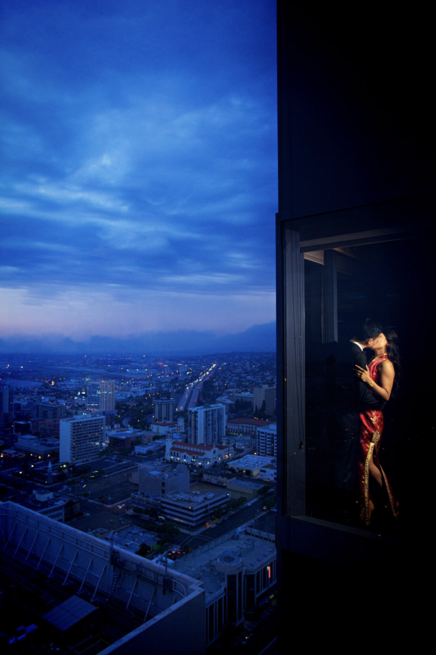 couple shares a kiss by a window amidst a urban backdrop