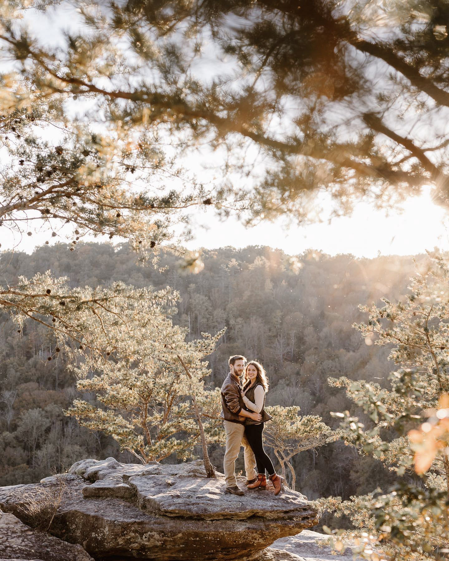 a couple standing on the edge of a cliff and posing holding each other