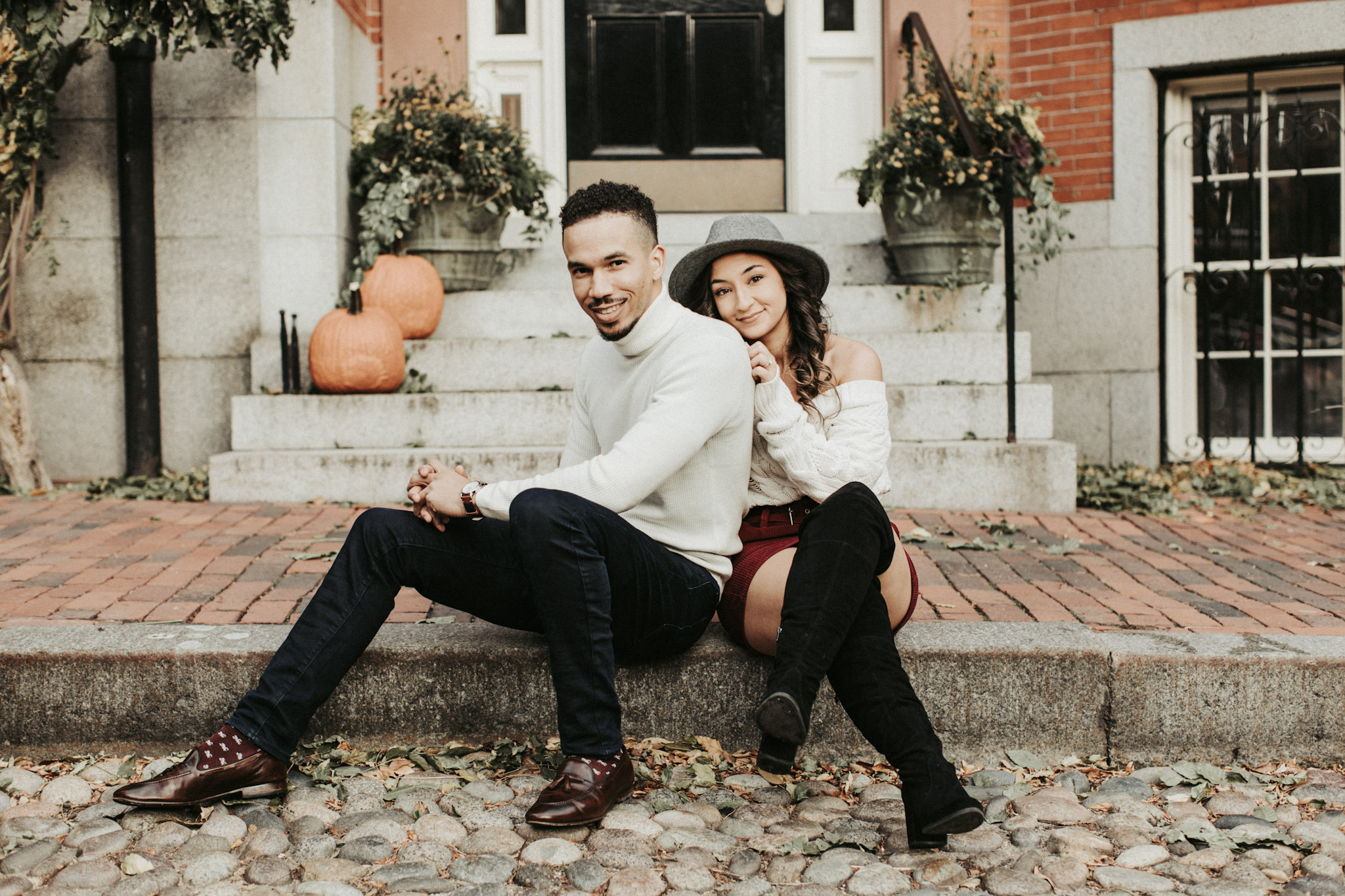 a couple posing while sitting on the sidewalk 