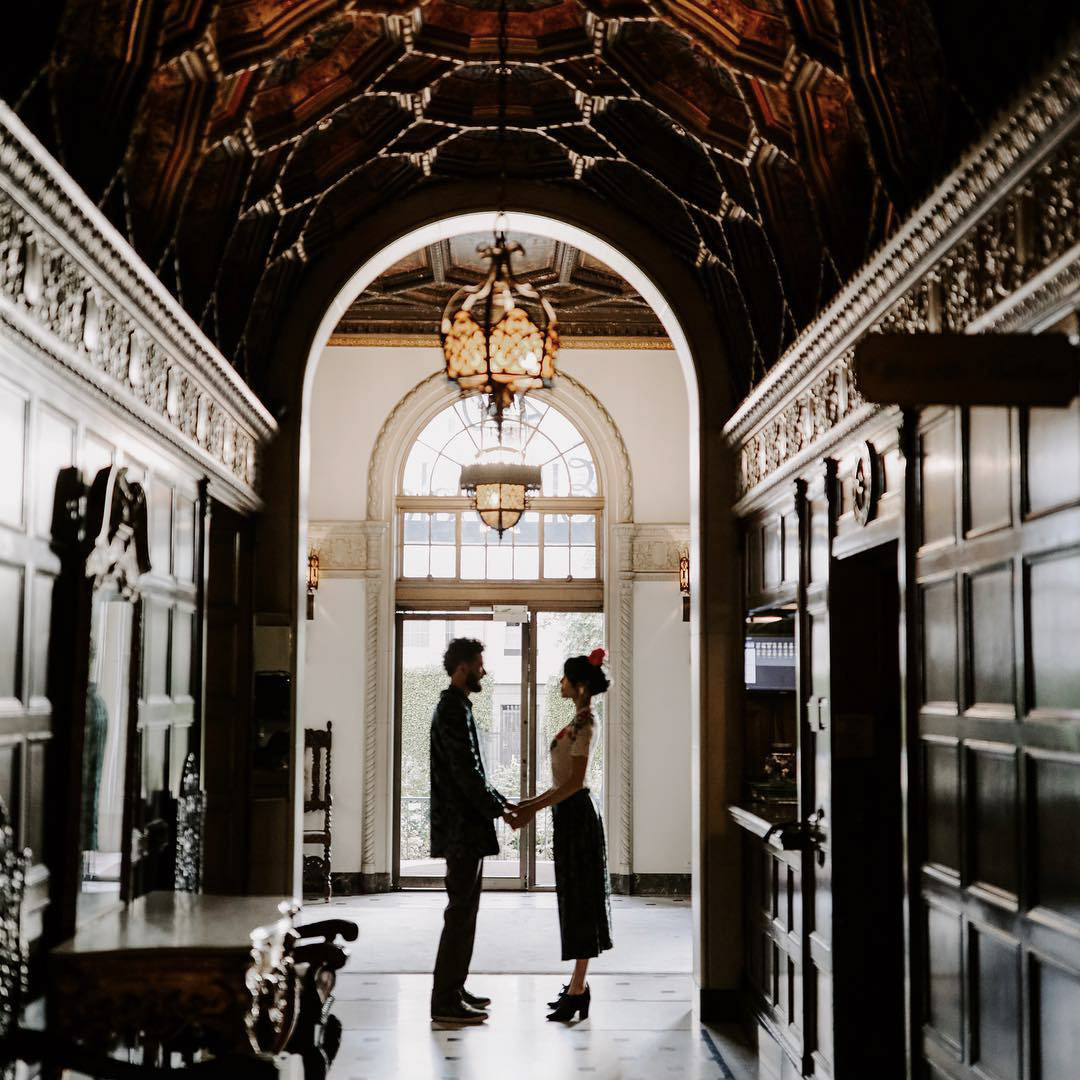a couple standing in a beautifully decorated hall holding hands
