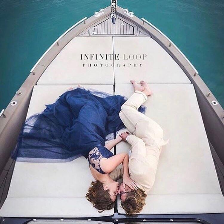 woman in blue dress with man in white suit laying on a boat