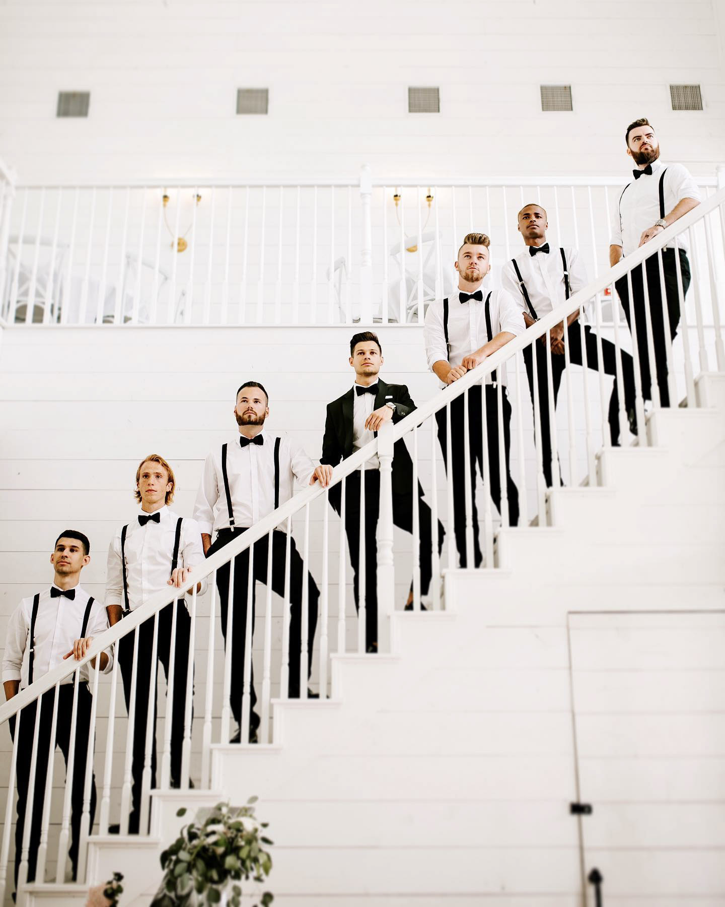 the groom and the groomsmen standing on a staircase posing in formal attire