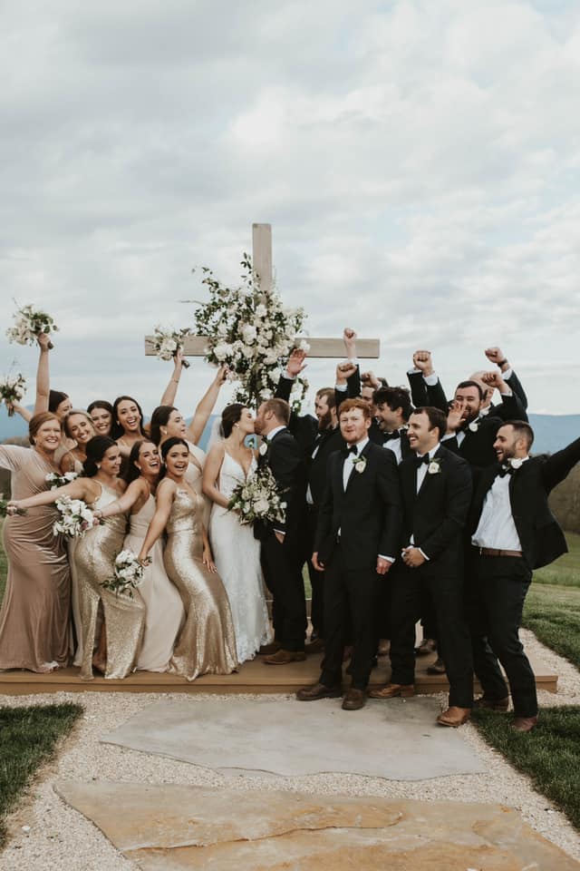 a wedding couple kissing while the bridesmaids and groomsmen are cheering standing around them