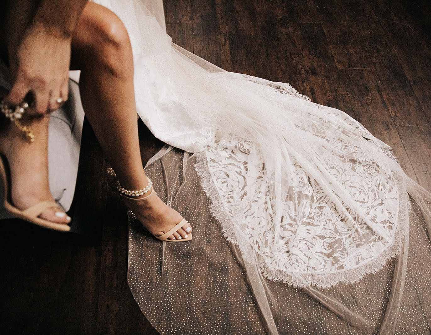 a creative perspective of a bride sitting with one leg on the train of the wedding dress
