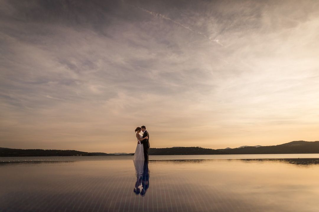 a couple embracing each other surrounded by water creating a beautiful reflection