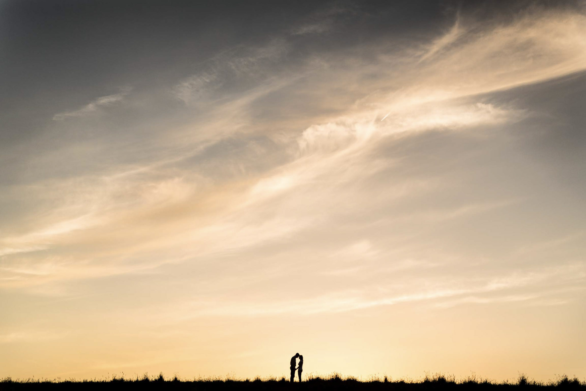 a beautiful wide angle silhouette of a couple with clear open skies