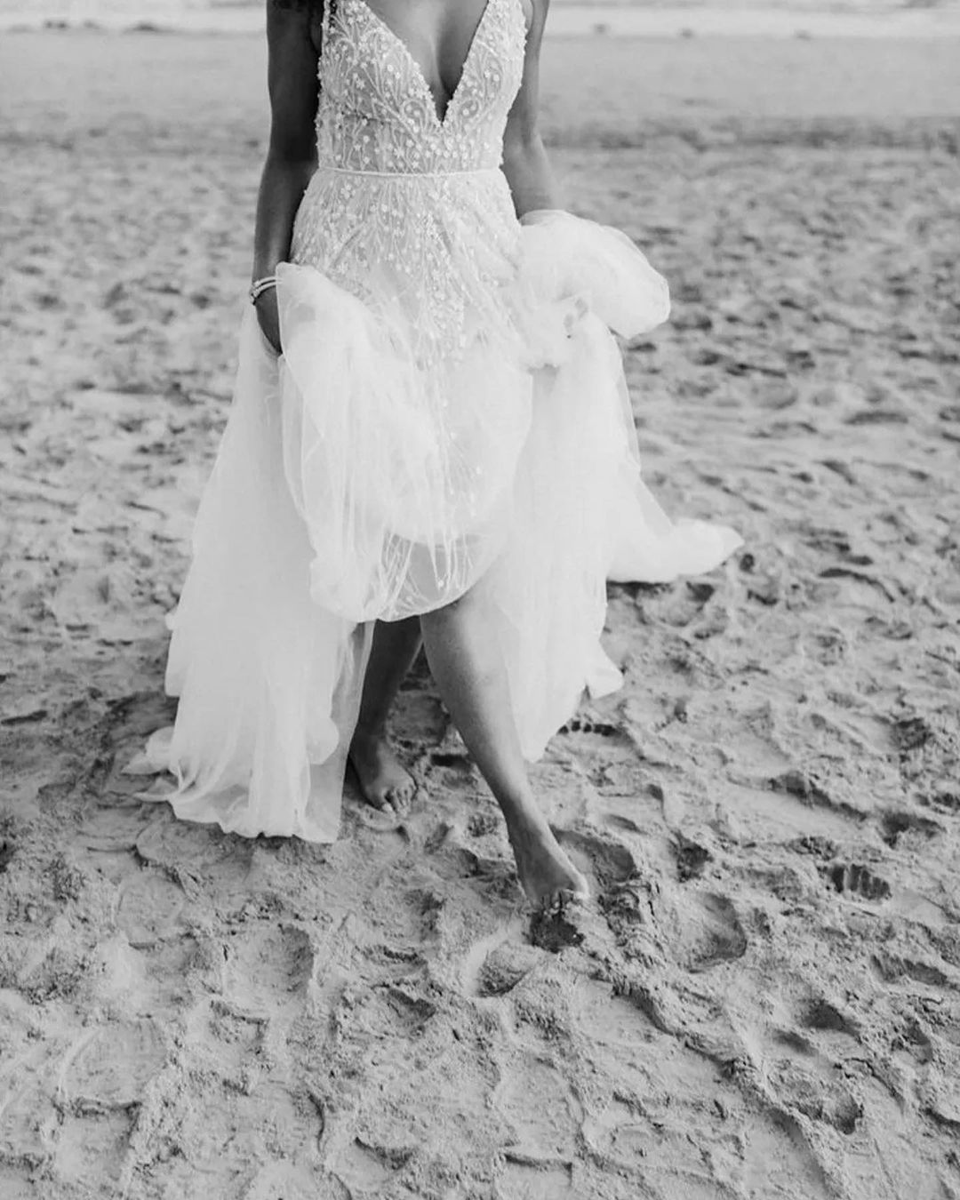 a bride in her bridal dress walking on sand barefoot in a beach
