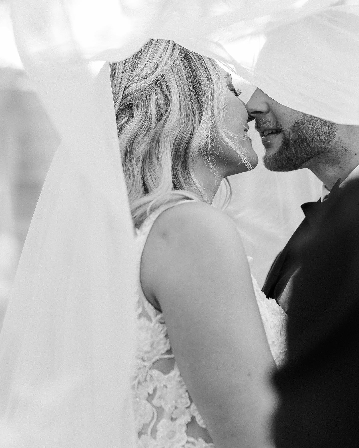 a black and white portrait of a couple sharing a intimate moment under the wedding veil