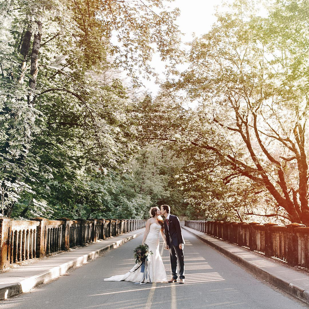a wedding bride and groom in their wedding attire kissing in the middle of a beautiful street