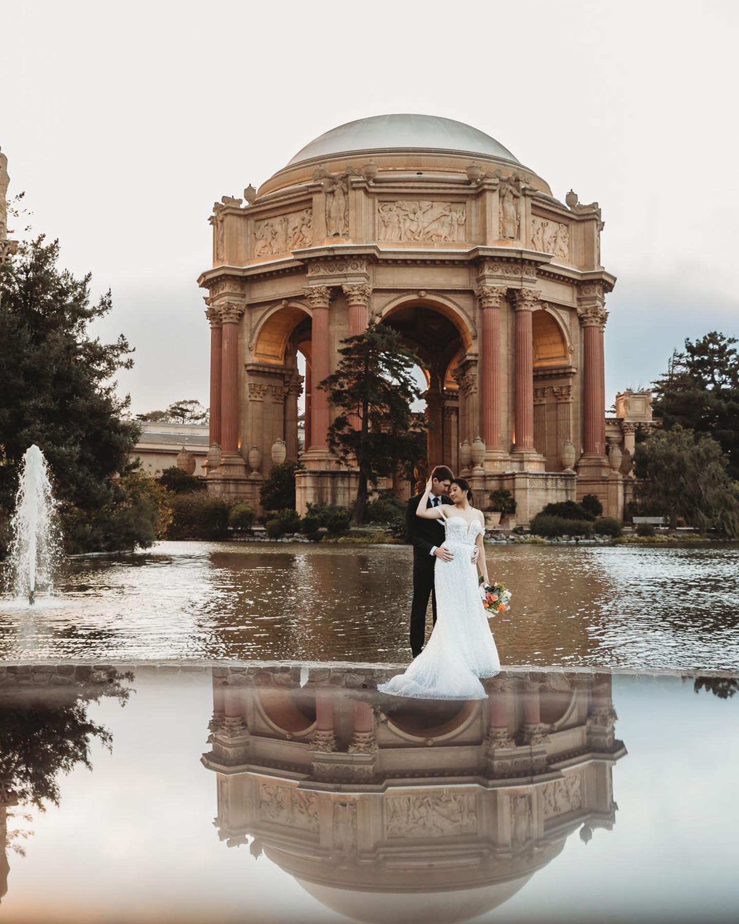 a couple posing in front of a beautiful landmark with fountains reflections in wedding photography