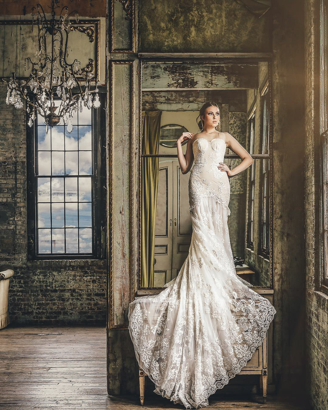 a bride posing in her wedding attire standing in a vintage room in front of a mirror reflections in wedding photography