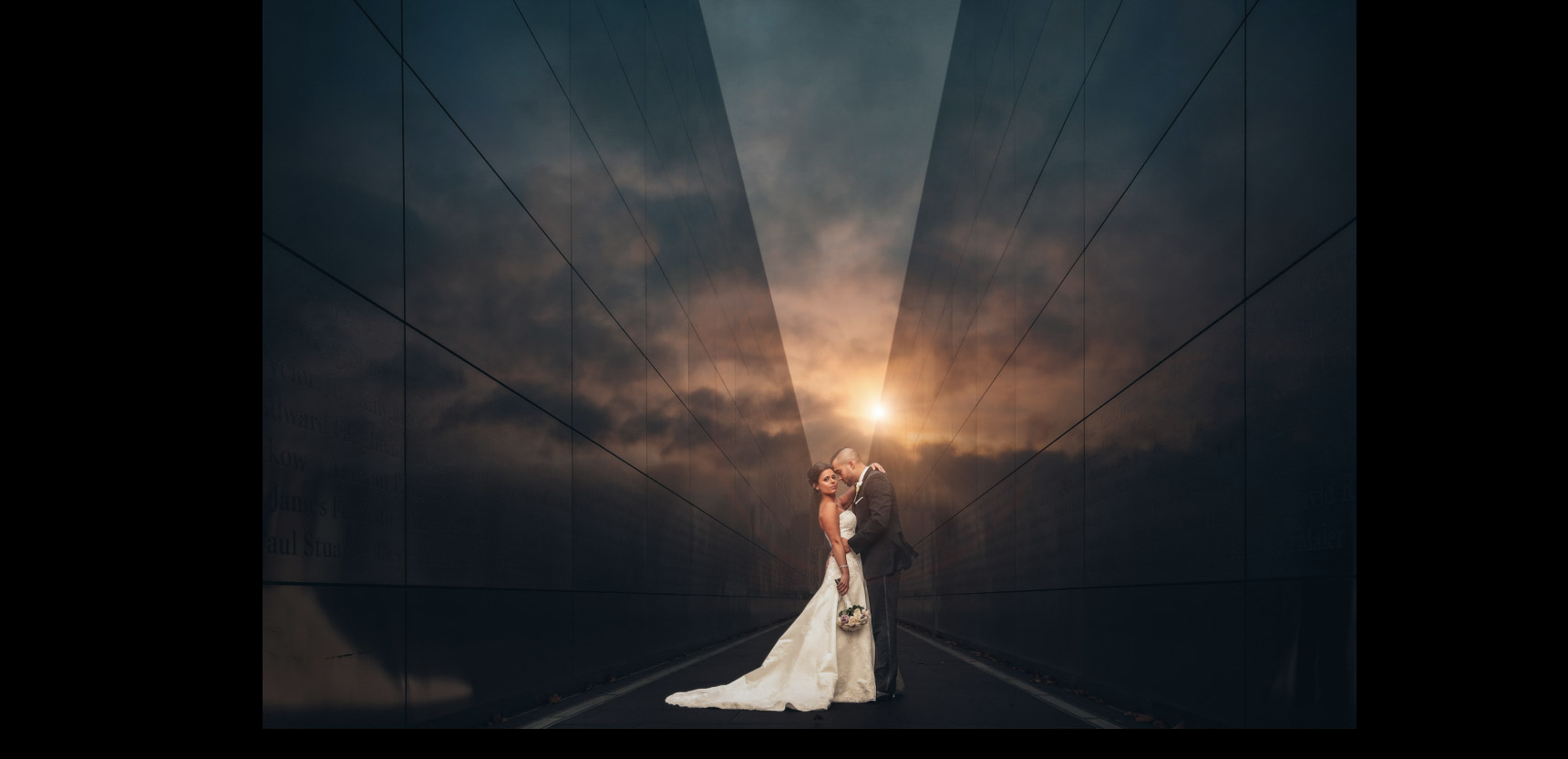 a couple standing in the middle of a two big reflective walls while the sun peeks from behind them