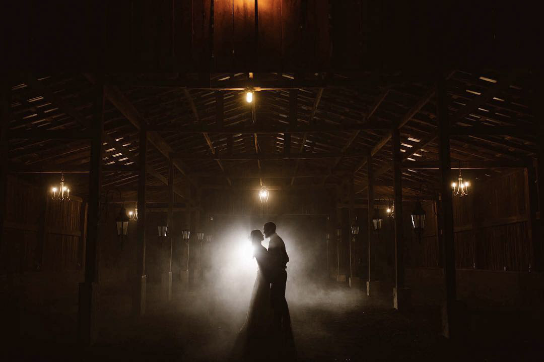 a silhouette of a wedding couple in a backlit barn setting