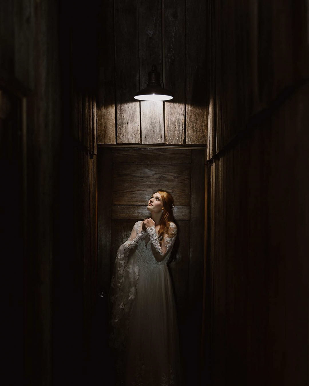 a bride in her wedding attire in a dimly lit room looking up