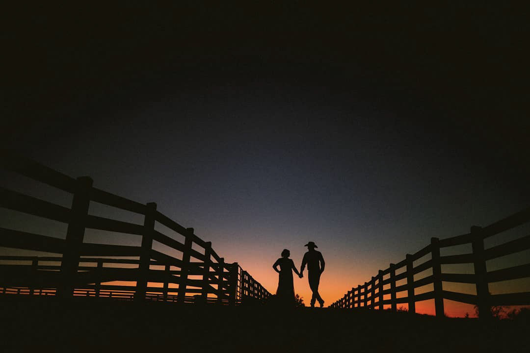 a silhouette of a wedding couple in a ranch at dusk