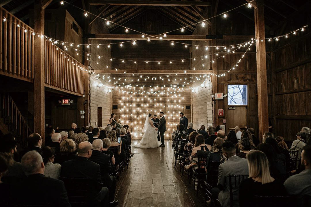 a beautiful dimly lit wedding ceremony in a rustic barn