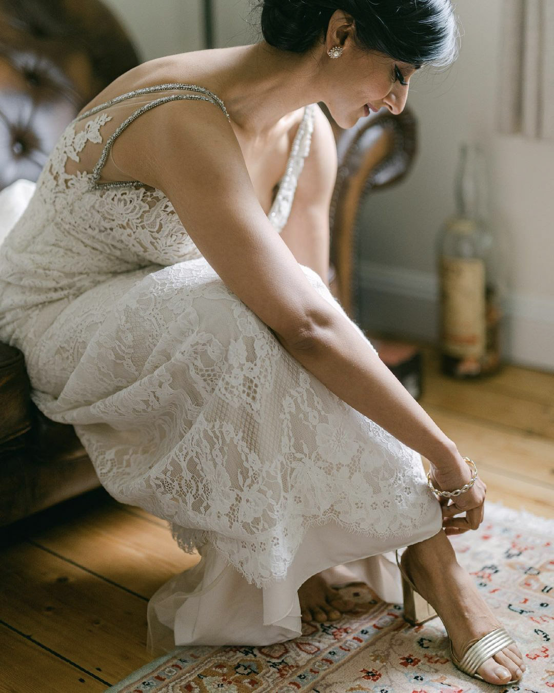 a bride getting ready strapping on her wedding shoes