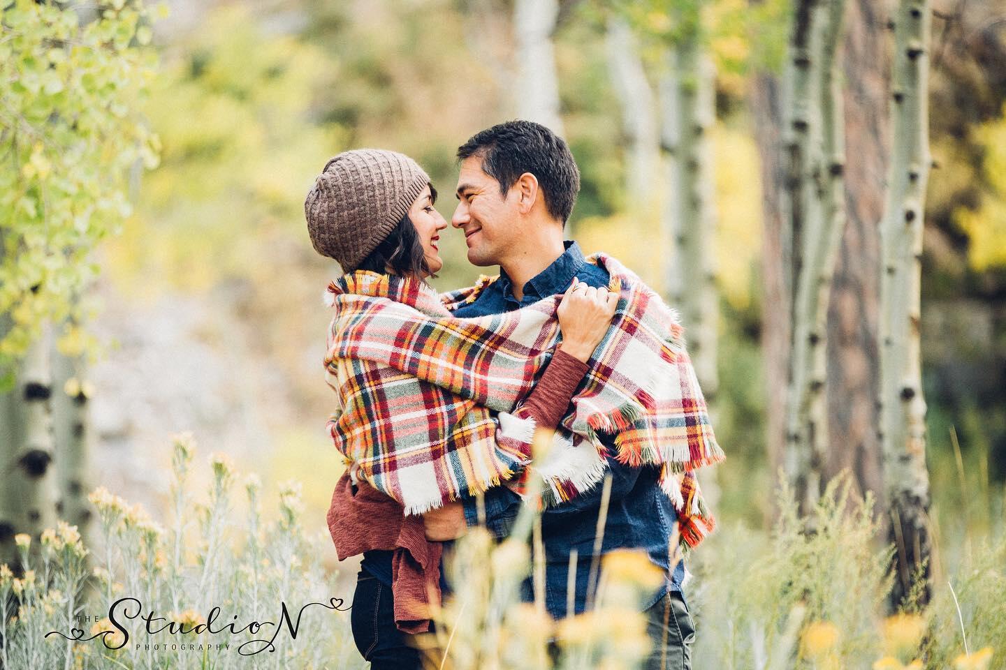 couple cuddling under a plaid blanket in the fall