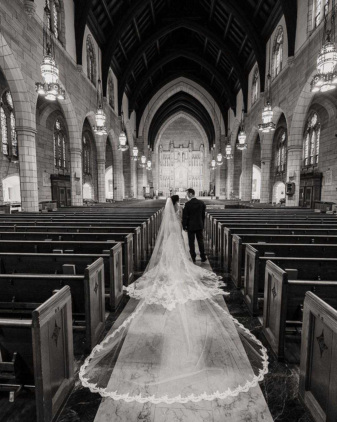 a wedding couple posing in a church in their wedding attire with the brides chapel train spread out beautifully