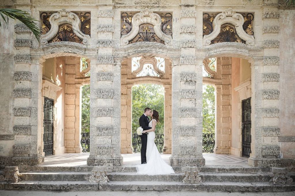 a wedding couple kissing standing on the stairs of a beautiful stone structure