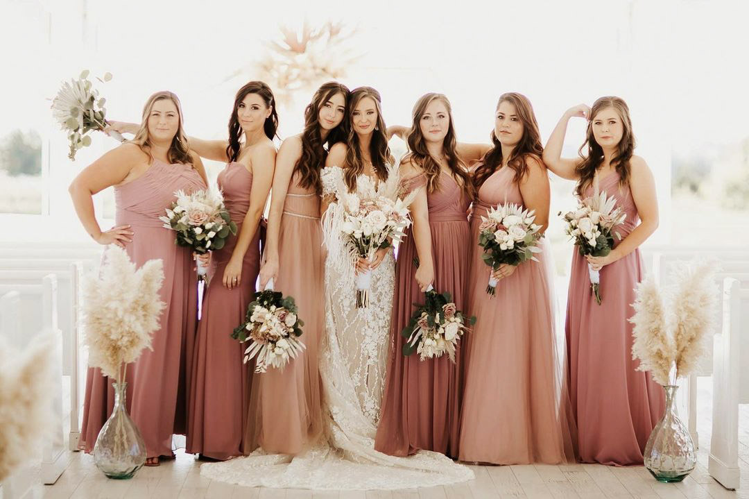 a wedding bride and her bridesmaids posing with the wedding bouquets