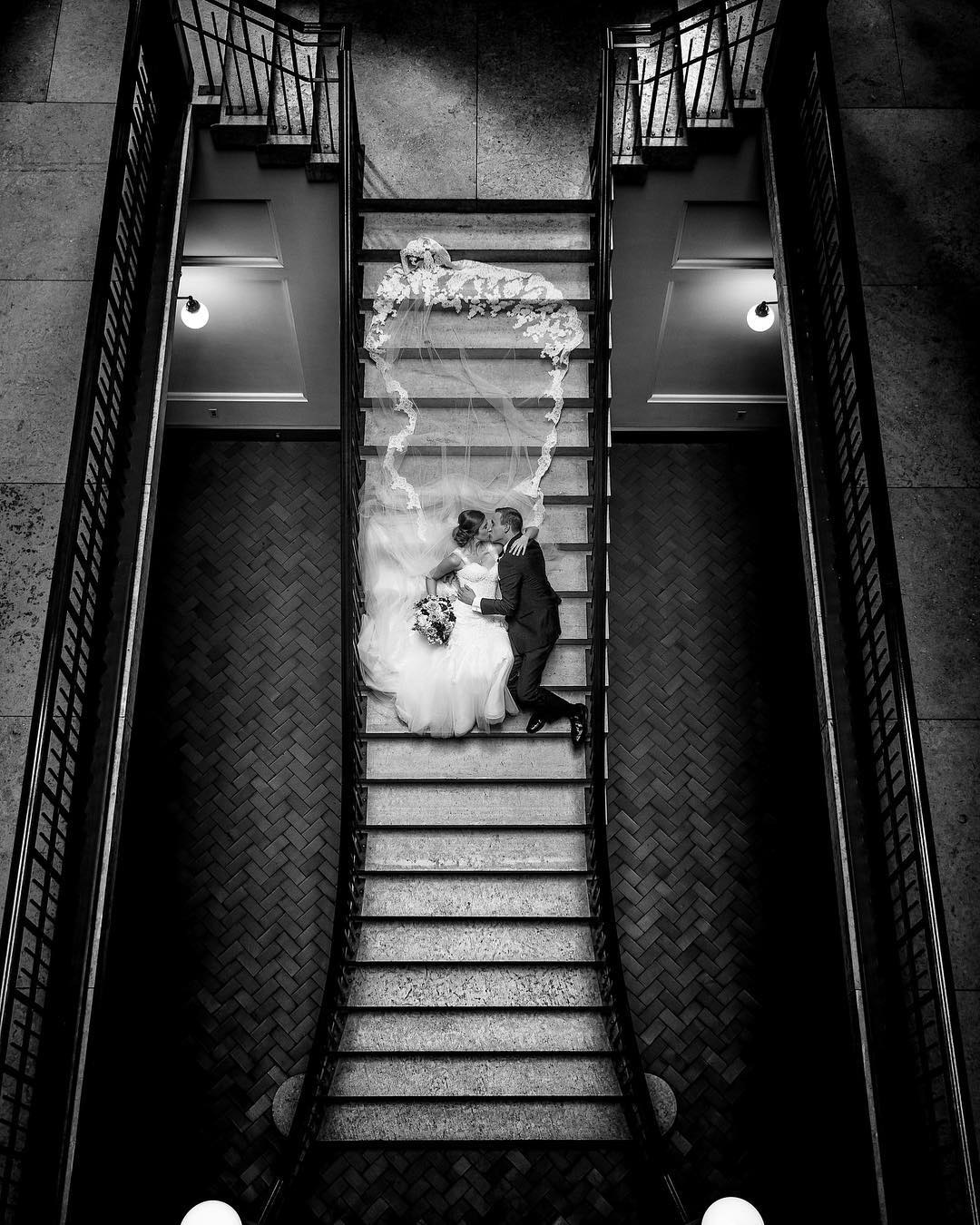 a wedding couple kissing lying down on the stairs in their wedding attire