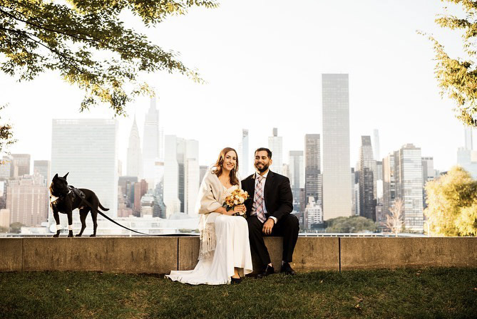 a wedding couple posing with their pet dog on a leash