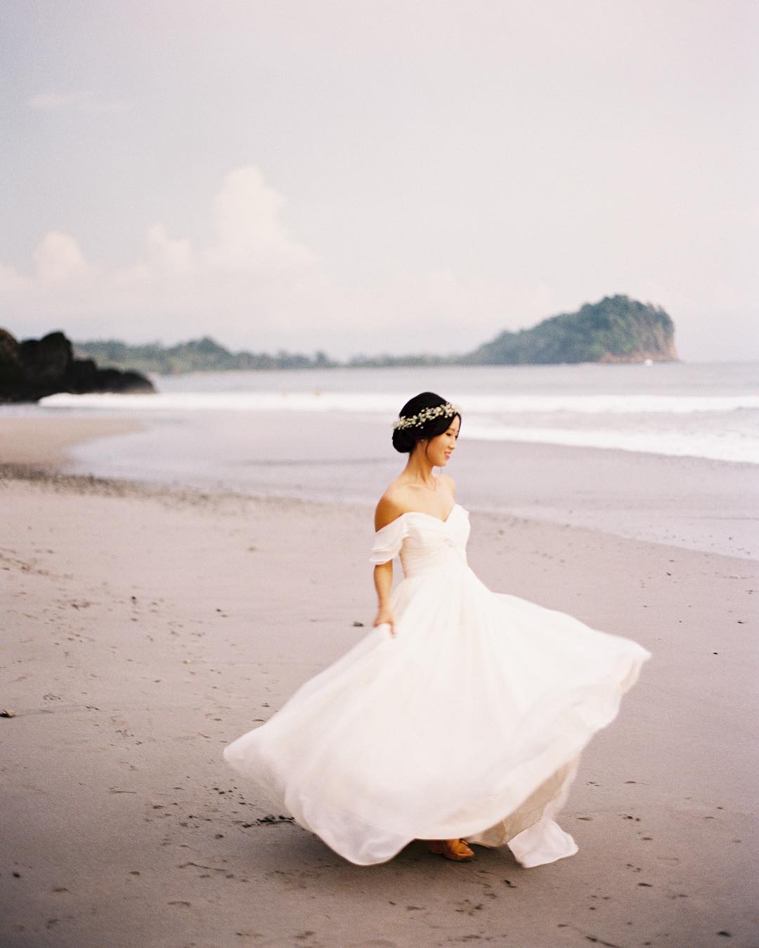 a wide in her wedding dress walking down the beach