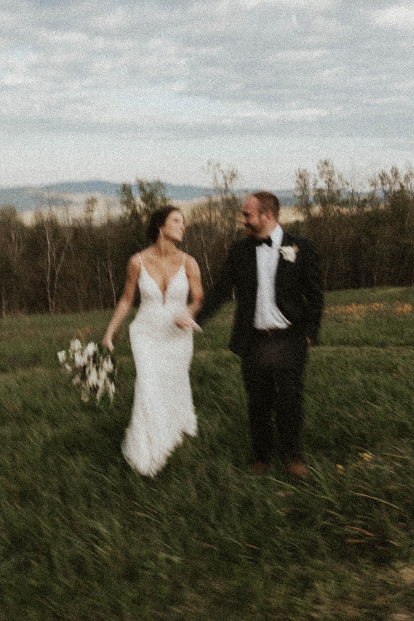 a blurry image of a wedding couple running through the fields