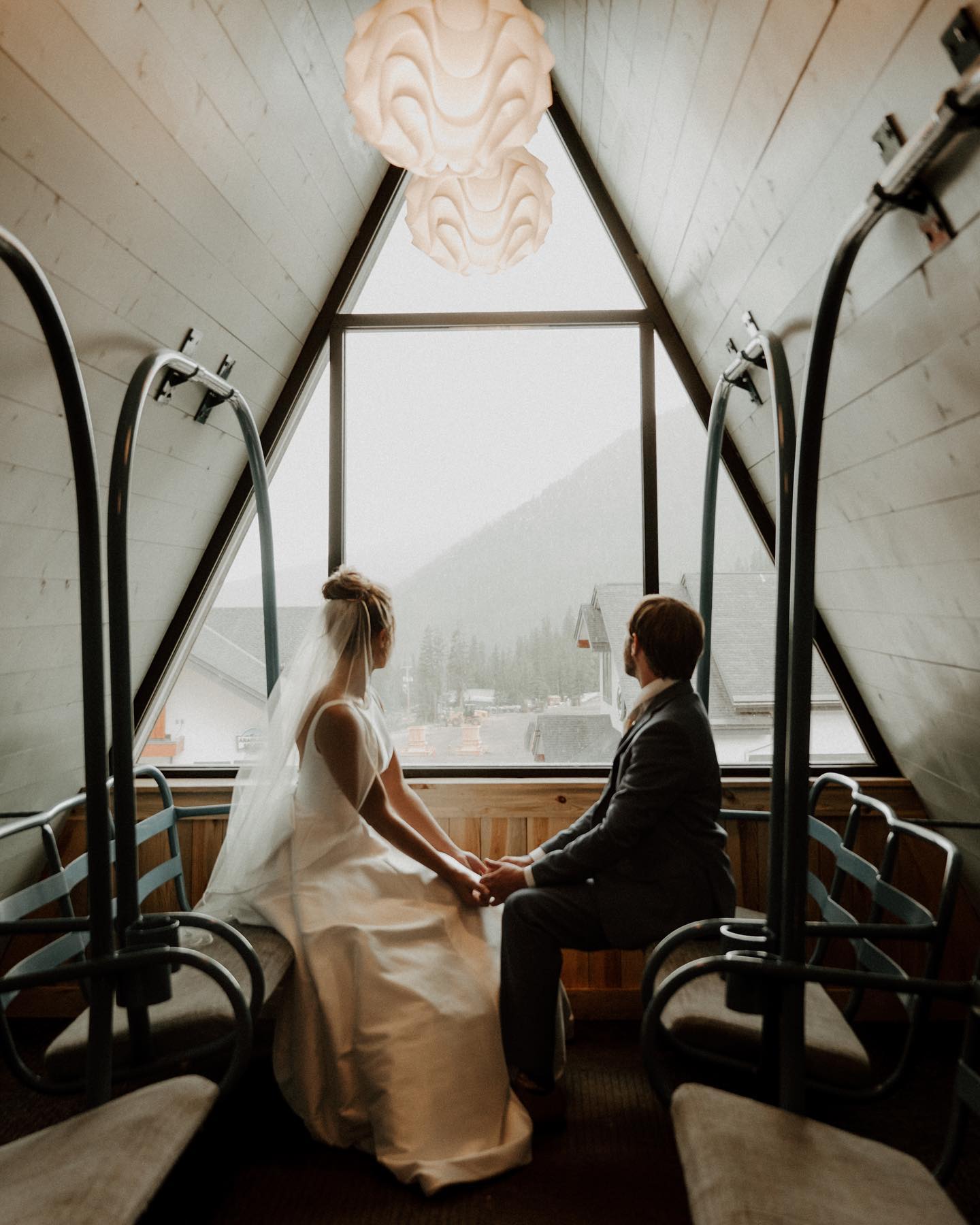a wedding couple holding hands and looking outside at a snowy landscape